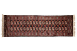 Vintage Bokhara rug runner with repeating columns of gul medallions in shades of rust, ivory, and black.