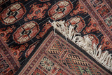 Corner view of a Bokhara rug showing its tight weave, intact side cord, and plush wool pile.