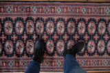 Plush Bokhara rug runner displaying geometric gul medallions in navy, brick red, and ivory.