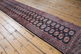 Bokhara runner's intricate flat-woven end with geometric patterns, navy, brick red, and ivory.