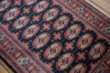 Bokhara rug's detailed brick red gul medallions, ivory accents, and navy geometric border.