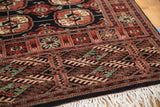 Detailed view of plush Bokhara rug's rust, black, and ivory geometric medallions with white fringe.