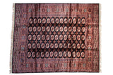 Vintage fine Bokhara carpet with repeating red and ivory gul medallions on a lustrous charcoal black field.