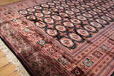 Lustrous wool pile and detailed border of a fine Bokhara carpet, shown at an angle.
