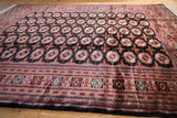 Angled view of a vintage Bokhara carpet's lustrous pile, showcasing the repeating gul medallion pattern.