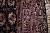 Detailed corner of a vintage Bokhara carpet showing the plush wool pile, intricate borders, and fringe.