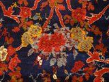Finely knotted rose bouquets in red, gold, and powder blue contrast with the dense navy blue wool pile.