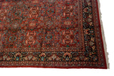 Corner view of a vintage Mahal carpet's elaborate floral border and ivory fringe.