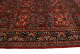 The intricate floral border and dense, brick-red field of a hand-knotted vintage Persian Mahal carpet.