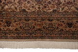 Close-up of the vintage Pakistani carpet's corner showing the floral border and intact ivory fringe.