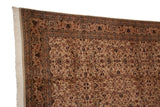 Corner of a vintage Pakistani carpet showing the original side cord, floral border, and clean ivory fringe.
