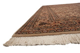 Angled view of a vintage Isfahan rug's corner, showing the dense wool pile and clean ivory fringe.