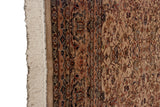 Close-up of a vintage rug's intact selvage, ivory fringe, and plush, floral wool pile.