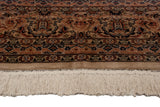 Detail of a vintage Pakistani rug's hand-knotted floral border and its intact ivory wool fringe.
