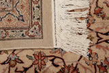 Close view of a vintage carpet's intact side selvage, hand knotted back, and clean ivory fringe.