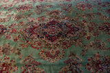 Intricate central medallion and vibrant floral sprays on a mint green Kerman carpet.