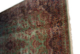 Vintage Kerman carpet with mint green field, red blossoms, navy border, and secured fringe.