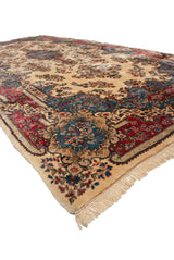 Corner detail of a vintage Kerman carpet's plush pile, ivory fringe, and contoured border.