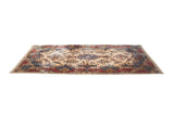 Vintage Kerman carpet viewed from a low angle, showing its floral field and elaborate blue and red border.