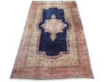 Vintage Kerman carpet with an ornate ivory medallion on a navy blue field and intricate rose floral borders.