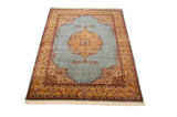 Angled view of a vintage Tabriz design carpet showing its saffron medallion and powder blue open field.
