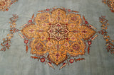 A close view of the saffron yellow scalloped medallion with mauve accents on a powder blue vintage rug.