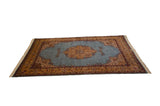 Angled view of the vintage Tabriz design carpet's powder blue field, medallion, and saffron border.