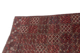 Angled view of an antique Beshir carpet's geometric multi-panel design and original side selvage.