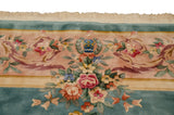Weaver insignia framed by rose bouquets and scrolling vinery on the green Savonnerie rug.