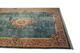 Corner of vintage Savonnerie rug with ocean green field, rose vinery border, and fringe.