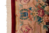 Cream fringe, black cherry red border, and blue gold weaver insignia among floral Savonnerie motifs.