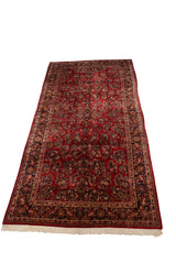 Angled perspective of a vintage Sarouk carpet, displaying its cherry red field and intricate floral design.