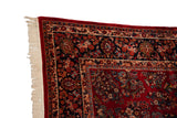 Close-up of the vintage Sarouk corner, detailing the navy palmette border and secured ivory fringe.