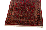 Angled view of a vintage Sarouk carpet's corner, highlighting its navy floral border and clean ivory fringe.
