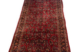 Angled view of the long vintage Sarouk carpet showing its allover floral bouquets and slight contour.