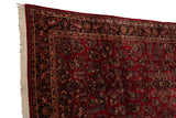 Angled corner view of a vintage Sarouk carpet's intact selvage and intricate navy border.
