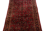 Longitudinal view of a vintage Sarouk carpet's cherry red field covered in repeating floral bouquets.