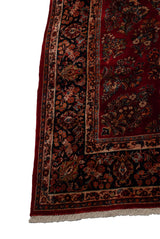 Intricate navy floral border, cherry red field, and ivory fringe on a vintage American Sarouk carpet.