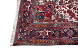 Detail of a vintage Mehrivan carpet corner with its geometric navy border and ivory fringe.