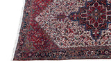 Angled corner of a vintage Mehrivan carpet showing the full pile, geometric navy border, and red field.