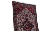 Hand-knotted carpet corner showing the full pile, navy geometric border, and ivory medallion field.