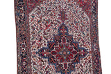 Angled view of a vintage Persian Mehrivan carpet's large geometric medallion and intricate ivory field.