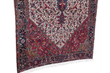 Side view of the vintage Persian carpet's intricate navy border, wool pile, and clean white fringe.