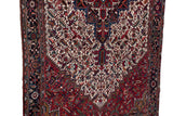 Intricate geometric patterns with serrated leaves in cherry red and navy on a vintage Persian rug.
