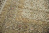 Vintage Agra carpet with dusty gold Herati border and floral motifs in greens and reds.