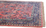 Vintage Sarouk rug featuring ruby red field, navy blue boteh paisley border, intact fringe.