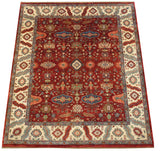 Angled view of a vintage Heriz carpet's repeating geometric floral gul design on a cherry red field.