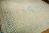 Angled view of the vintage rug's soft blue scalloped medallion and repeating floral borders.