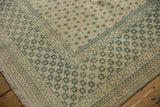 Corner of a vintage distressed carpet showing the worn floral lattice and border detail.