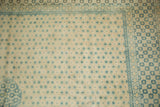 Corner of a distressed Bulgarian rug with soft blue lattice patterns against an ivory field and floral border.